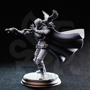 May include: A detailed, grayscale figurine of a person in a cloak, with a bird perched on their head and outstretched arms. The figure stands on a circular base with a cobblestone pattern. The overall design suggests a fantasy or historical theme.