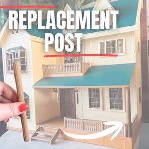 Puede incluir: Un poste de repuesto para una casa de muñecas, sostenido frente a la casa en miniatura. La casa de muñecas tiene un exterior amarillo, un techo verde azulado y molduras blancas. El texto "REPLACEMENT POST" se muestra en letras blancas.