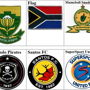 Può includere: Una collezione di loghi di club calcistici sudafricani. I loghi includono Kaizer Chiefs, FA, Mamelodi Sundowns, Bidvest Wits, Manning Rangers, Orlando Pirates, Santos FC e SuperSport United. Viene mostrata anche la bandiera sudafricana.