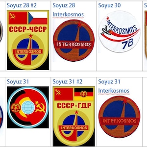 May include: A collection of eight embroidered patches from the Soviet Interkosmos program. The patches feature the flags of the Soviet Union and various other countries, including Czechoslovakia, Poland, and East Germany. Each patch also includes the text "INTERKOSMOS" and a rocket design.