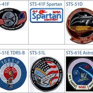 May include: A collection of nine NASA Space Shuttle mission patches. The patches are circular and feature a variety of designs, including the Space Shuttle, the American flag, and the names of the astronauts who flew on the missions. The patches are all embroidered and have a variety of colors, including red, white, blue, black, and gold.
