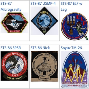May include: A collection of nine space mission patches, each with a unique design and color scheme. The patches feature various symbols, including stars, planets, and spacecraft. The patches are arranged in a grid format, with three rows and three columns.