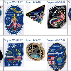 May include: A collection of eight embroidered patches featuring the Soyuz spacecraft. The patches are in various colours and designs, including blue, red, white, and gold. Each patch features the Soyuz spacecraft and the mission number. The patches are arranged in two rows of four.