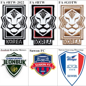 Può includere: Una collezione di nove toppe ricamate con vari loghi ed emblemi di squadre di calcio coreane. I design includono toppe rettangolari e a forma di scudo con testo come KOREA, SEOUL, JEONBUK e SUWON, realizzate in rosso, nero, bianco, blu e oro.