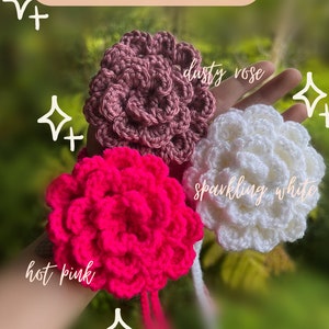 May include: Three crocheted flower shapes in dusty rose, sparkling white, and hot pink.  The flowers are held in a hand.  The text "NEW COLORS!" is at the top of the image.