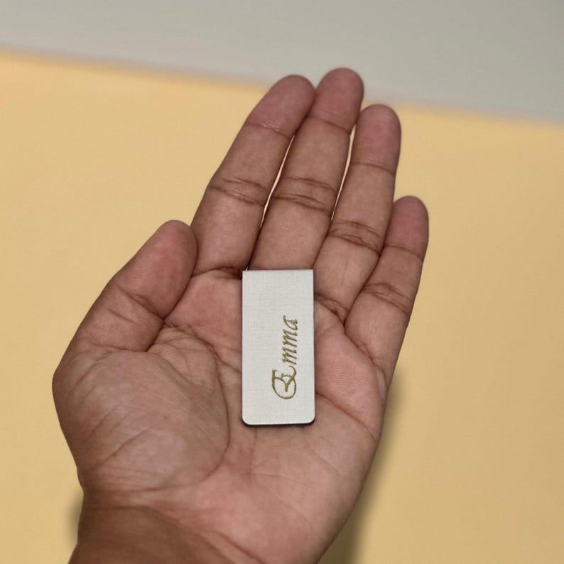 May include: White personalised money clip with the name "Emma" engraved in gold lettering.