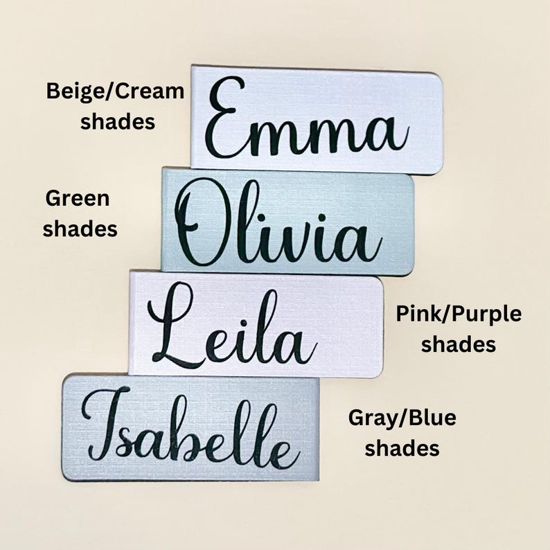 May include: Four personalised name plaques in different colours. The names are Emma, Olivia, Leila, and Isabelle. The plaques are in beige, green, pink, and grey shades.