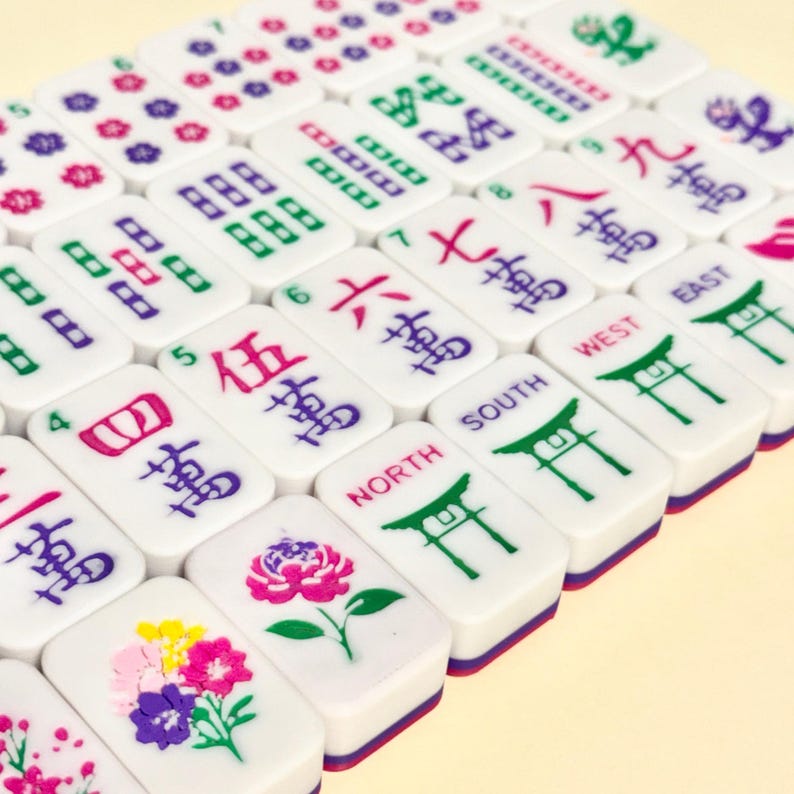 May include: A collection of white Mahjong tiles with various symbols and numbers in red, green, purple, and black. Some tiles feature floral designs. The tiles are arranged in a diagonal pattern.