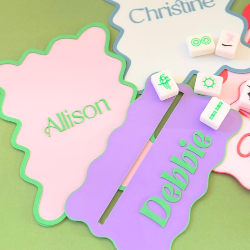 May include: Three personalized name tags with scalloped edges and green trim. The tags are pink, purple, and blue. The names "Allison", "Debbie", and "Christine" are written in green on the tags.