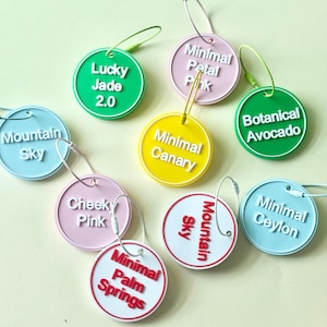 May include: A collection of colorful, round tags with various text labels. The tags are in shades of green, pink, yellow, and blue, with white text. Some tags include the phrases "Lucky Jade 2.0", "Minimal Petal Pink", and "Botanical Avocado".