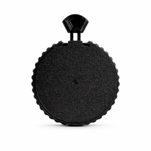 May include: A black, circular bottle stopper with a textured surface and a small handle. The stopper has a ridged edge and a small, hexagonal handle for easy gripping. The design is simple and modern.
