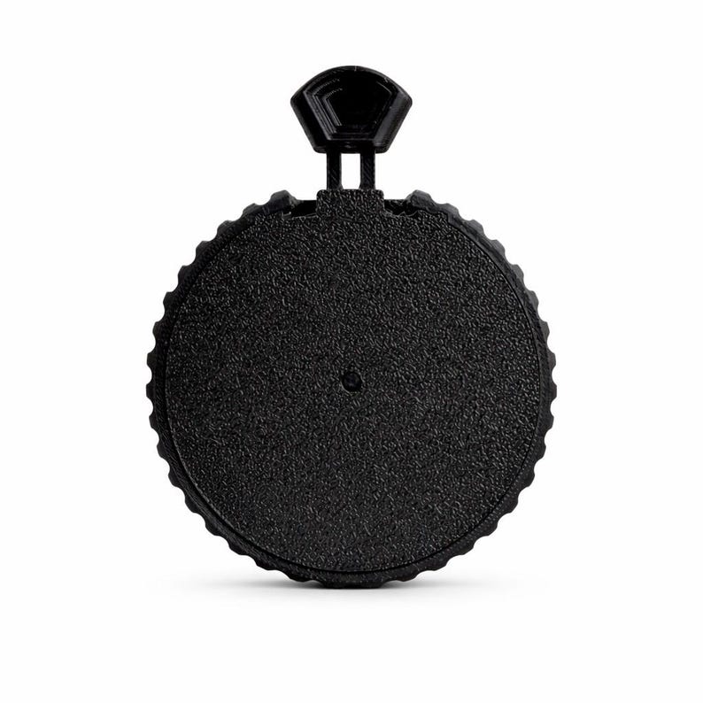 May include: A black, circular bottle stopper with a textured surface and a small handle. The stopper has a ridged edge and a small, hexagonal handle for easy gripping. The design is simple and modern.