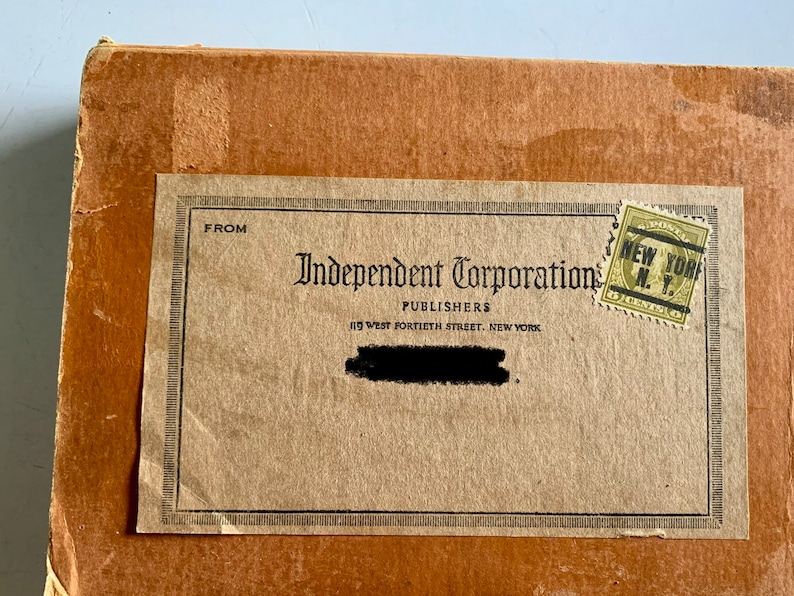 K&ouml;nnte beinhalten: Ein brauner Karton mit einem Etikett mit der Aufschrift "From Independent Corporation Publishers 119 West Fortieth Street, New York" und einer "New York N.Y." Briefmarke.
