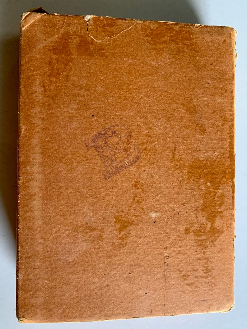 K&ouml;nnte beinhalten: Ein brauner Karton mit einem abgenutzten und verblassten Aussehen. Der Karton hat einen kleinen, verblassten lilafarbenen Stempel auf der Vorderseite.