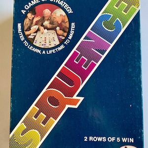 May include: A blue game box with a colorful diagonal word "SEQUENCE" on the front. The box features a game board with three people playing. The text on the box reads "A game of strategy, minutes to learn, a lifetime to master, 2 rows of 5 win".