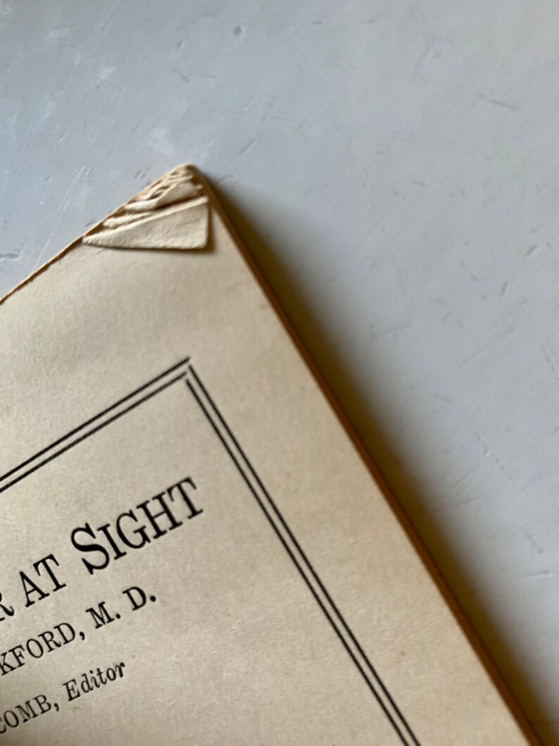 K&ouml;nnte beinhalten: Nahaufnahme des Einbands eines Buches mit dem Titel "At Sight" von K. Ford, M.D. Unter dem Titel steht der Text "Comb, Editor".