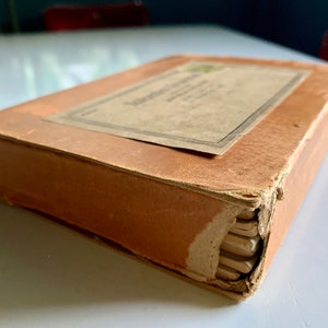 K&ouml;nnte beinhalten: Eine alte braune Schachtel aus Pappe mit einem Etikett mit der Aufschrift "The American Crayon Company, Sandusky, Ohio, U.S.A."