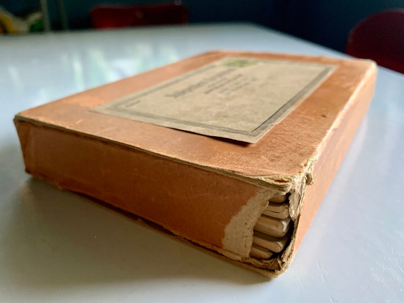 K&ouml;nnte beinhalten: Eine alte braune Schachtel aus Pappe mit einem Etikett mit der Aufschrift "The American Crayon Company, Sandusky, Ohio, U.S.A."