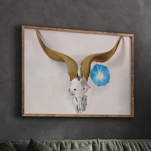 May include: A framed print of a white animal skull with large, curved horns. A blue flower with a yellow center is positioned above the skull.