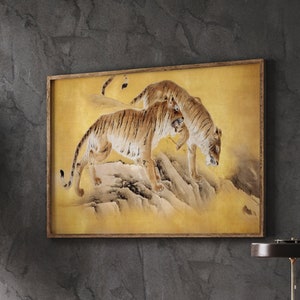May include: A framed print of two tigers walking on a rocky mountain path. The tigers are brown and orange with black stripes. The background is a light yellow with a watercolor effect.