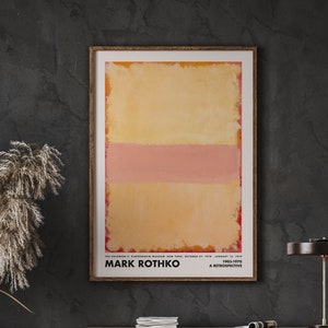 May include: A framed poster of an abstract painting by Mark Rothko. The painting features a yellow background with a horizontal pink stripe. The poster includes the text "Mark Rothko 1903-1970 A Retrospective".