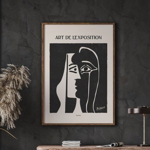 May include: A black and white art print featuring a stylized portrait of a woman's face. The print is titled "Art de l'Exposition" and is signed "Picasso".