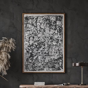 Puede incluir: Una impresión de arte abstracto en blanco y negro en un marco de madera, colgada en una pared gris oscuro sobre una mesa consola de madera con un sofá de cuero marrón delante.