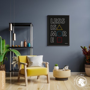 May include: A black and white print with the text "Less is More" in white with a yellow triangle, blue circle, and red square. The print is framed in black and hanging on a dark blue wall. A yellow armchair with a white pillow is in the foreground.