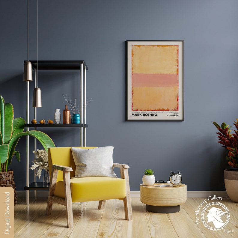 May include: A yellow armchair with a white pillow sits in a room with a dark blue wall. A black metal shelf with a few decorative items is in the background. A framed poster with the text "MARK ROTHKO" is on the wall. A small wooden side table with a clock and a potted plant is in the foreground.