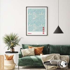 May include: A digital download of a minimalist poster featuring a blue and white wave pattern with the Japanese text "浪北斎" (meaning "Great Wave" by Hokusai) in red. The poster is framed and hanging on a white wall above a green sofa with cushions and a throw blanket.