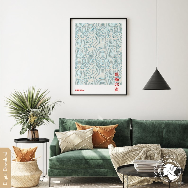 May include: A digital download of a minimalist poster featuring a blue and white wave pattern with the Japanese text "浪北斎" (meaning "Great Wave" by Hokusai) in red. The poster is framed and hanging on a white wall above a green sofa with cushions and a throw blanket.