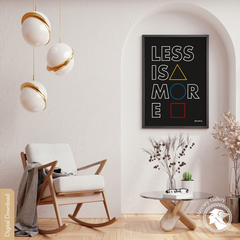 May include: A black and white poster with the text "LESS IS MORE" in white letters. The letters are outlined in black and have colored geometric shapes behind them. The poster is hanging on a white wall in a room with a rocking chair and a coffee table.