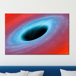 May include: A canvas print depicting a black hole in space. The artwork features a swirling vortex of blue and white against a backdrop of red and orange hues. The image is mounted on a white wall above a blue sofa with white pillows.