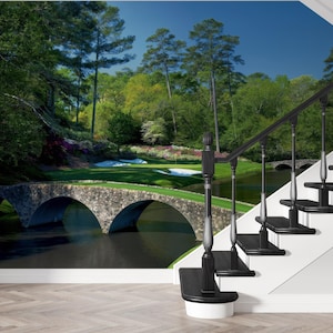 May include: A black metal staircase with a white handrail in front of a wall mural depicting a golf course with a stone bridge and lush green trees.