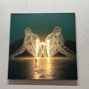 Könnte beinhalten: Eine leuchtende Drahtgitter-Skulptur von zwei Figuren, die sich gegenüberstehen, mit einer kleineren Figur, die im Vordergrund auf sie zugeht. Die Skulptur ist vor einem dunkelgrünen Hintergrund mit einer Wüstenlandschaft platziert.