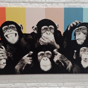 May include: A colorful canvas print featuring five chimpanzees with different expressions. The chimpanzees are arranged in a row, with the background behind them consisting of vertical stripes of orange, yellow, pink, blue, and light blue.