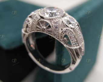 May include: A silver ring with a large, round, clear gemstone surrounded by smaller, clear gemstones. The ring has a detailed, ornate design.