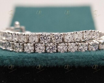 May include: A double row diamond tennis bracelet with a silver metal band. The bracelet is on a green velvet surface.