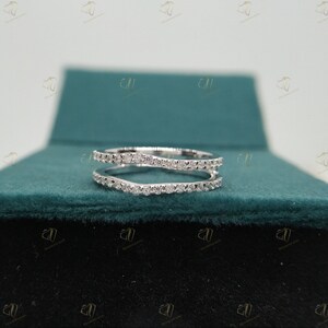May include: A delicate, white gold ring with a double band design. The ring is set with small, sparkling diamonds.