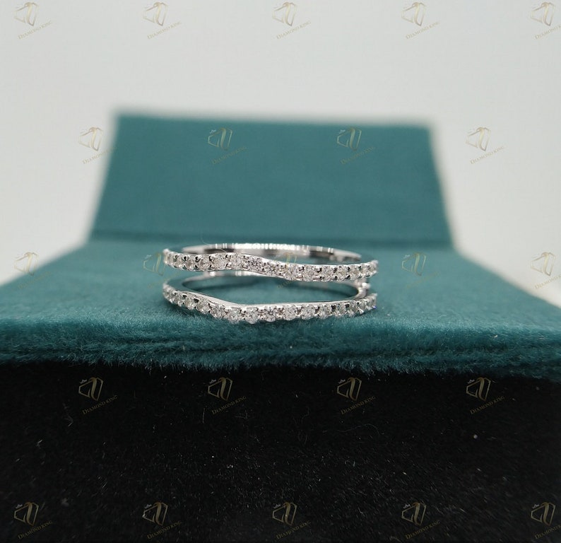 May include: A delicate, white gold ring with a double band design. The ring is set with small, sparkling diamonds.