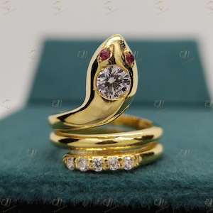Peut inclure: Une bague en or en forme de serpent avec un grand diamant rond et deux yeux en rubis rouge. La bague est ornée d'une bande de petits diamants.