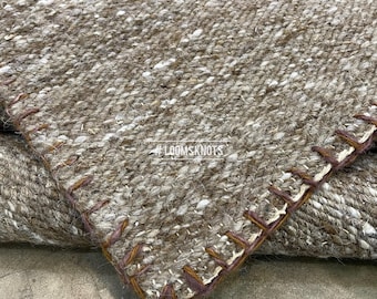 May include: Close-up of a woven rug with a textured, neutral color palette. The rug features a mix of brown, beige, and white threads, with visible stitching along the edges. The text "#LOOMSKNOTS" is visible in the corner.