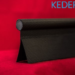 Puede incluir: Un producto de tela negra texturizada con una parte superior redondeada y una base triangular, sobre un fondo rojo. El producto tiene un patrón tejido y un acabado oscuro y mate. El texto "KEDER UK" es visible en la esquina superior derecha.