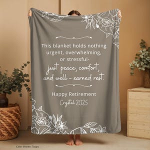 Peut inclure: Couverture taupe avec des motifs floraux blancs et du texte. Le texte se lit comme suit : &laquo; Ce plaid ne contient rien d'urgent, de bouleversant ou de stressant - juste la paix, le confort et le repos bien m&eacute;rit&eacute;. Joyeux d&eacute;part &agrave; la retraite Crystal 2025."