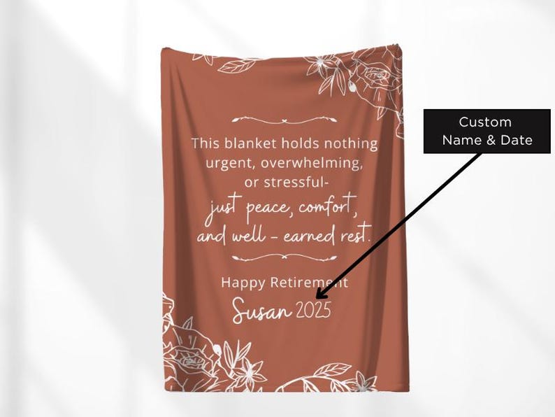 Peut inclure: Une couverture de couleur rouille avec des motifs floraux blancs et du texte. Le texte dit : &laquo; Ce plaid ne contient rien d'urgent, de bouleversant ou de stressant - juste la paix, le confort et le repos bien m&eacute;rit&eacute;. &raquo; Il dit aussi &laquo; Happy Retirement Susan 2025 &raquo;.