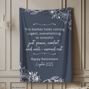 Peut inclure: Couverture bleu marine avec des motifs floraux blancs et du texte. Le texte dit : &laquo; Ce plaid ne contient rien d'urgent, accablant ou stressant - juste la paix, le confort et le repos bien m&eacute;rit&eacute;. Joyeuse retraite Crystal 2025. &raquo;