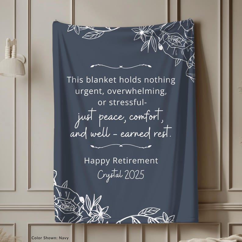 Peut inclure: Couverture bleu marine avec des motifs floraux blancs et du texte. Le texte dit : &laquo; Ce plaid ne contient rien d'urgent, accablant ou stressant - juste la paix, le confort et le repos bien m&eacute;rit&eacute;. Joyeuse retraite Crystal 2025. &raquo;