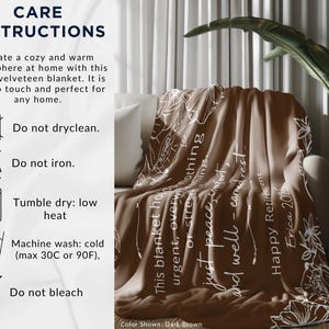 Peut inclure: Une couverture en velours pelucheux marron fonc&eacute; avec des motifs floraux blancs et du texte, drap&eacute;e sur un canap&eacute; blanc. Le texte de la couverture se lit comme suit : &laquo; Cette couverture contient des choses urgentes, accablantes ou stressantes...juste la paix, le confort et le repos bien m&eacute;rit&eacute;. &raquo; Instructions d'entretien visibles.