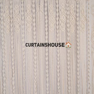 K&ouml;nnte beinhalten: Ein wei&szlig;er Makramee-Vorhang mit geometrischem Muster. Der Vorhang ist aus Baumwollschnur gefertigt und hat einen Fransen unten. Der Text "CURTAINSHOUUSE" ist in der Mitte des Bildes sichtbar.