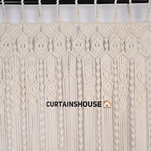K&ouml;nnte beinhalten: Ein wei&szlig;er Makramee-Vorhang mit geometrischem Muster. Der Vorhang ist aus Baumwollschnur gefertigt und hat einen Fransen unten. Der Text "CURTAINS HOUSE" ist unten in der Mitte des Bildes sichtbar.